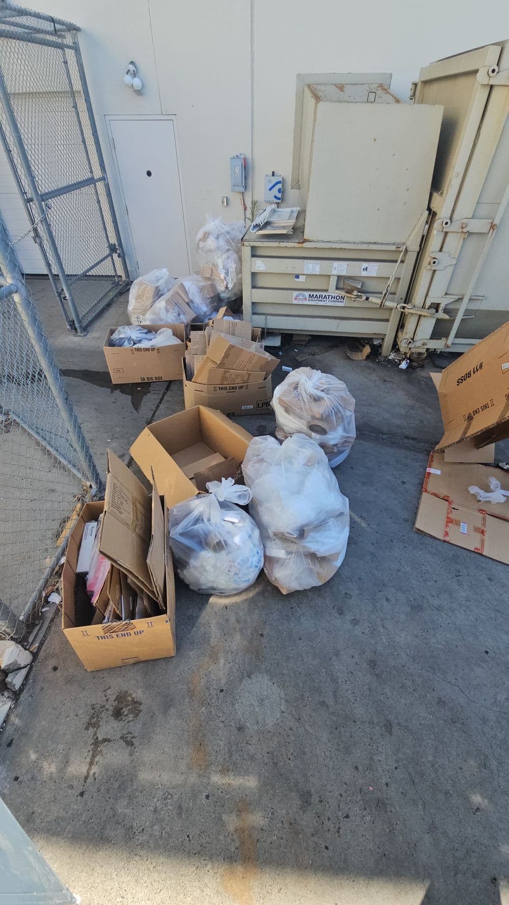 Overflowing trash and cardboard boxes in a commercial waste area.