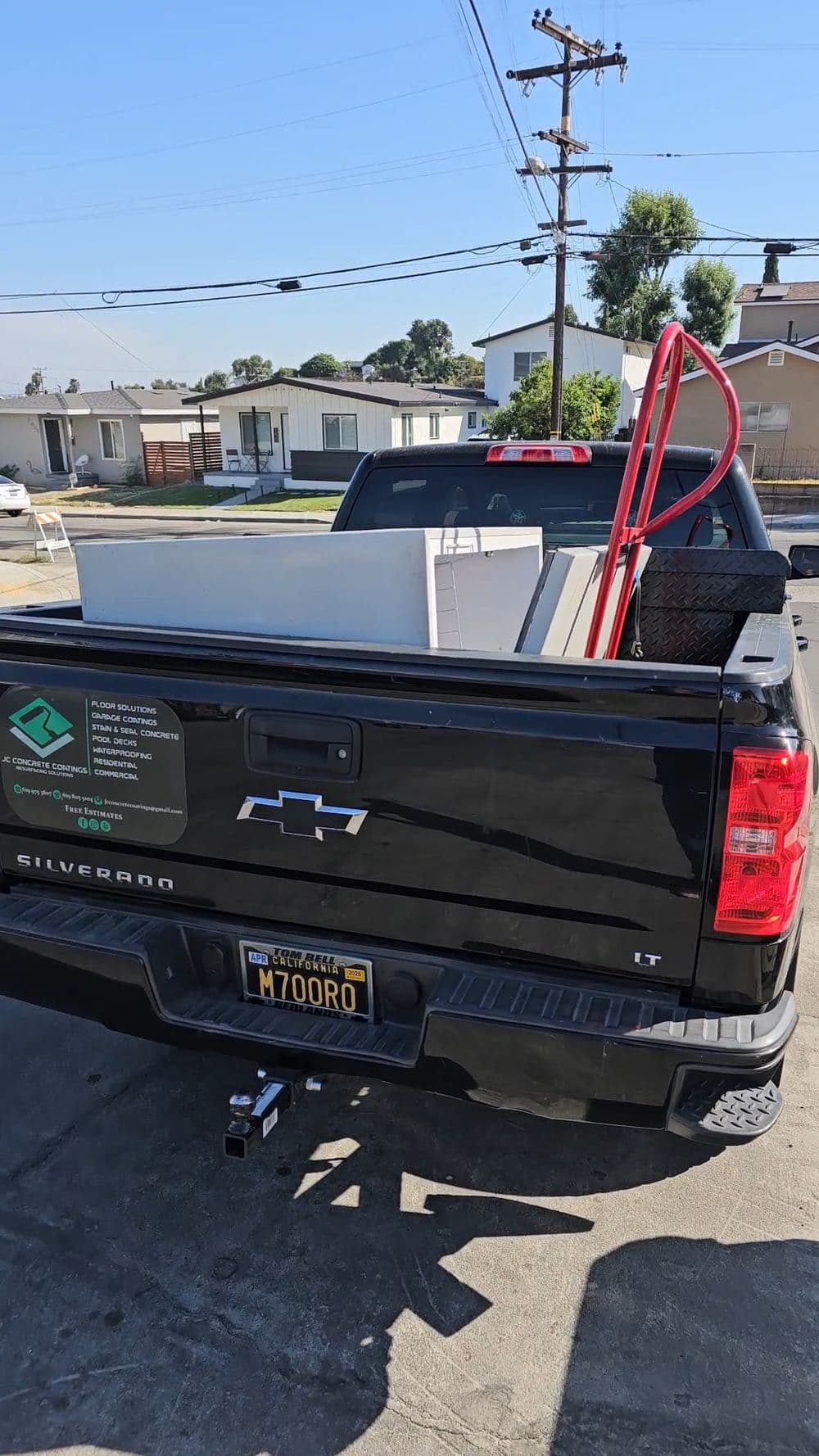 Black Chevrolet Silverado truck bed loaded with construction equipment and tools.
