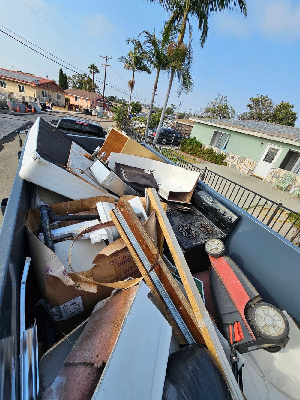 Dump truck filled with debris and construction waste on a residential street.